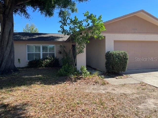 A single-story house with a tan exterior, a two-car garage, and a large front tree — 2230 BIRCHBARK TRAIL, CLEARWATER, FL