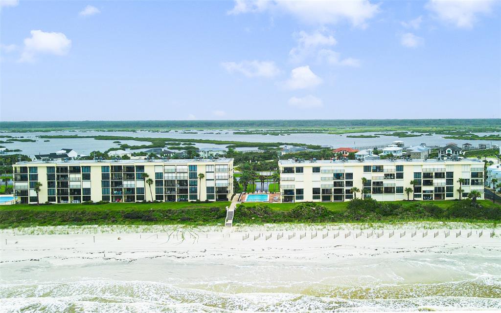 An aerial view shows two multi-story apartment buildings situated along a sandy beach — 7990 A1A S UNIT 404, ST AUGUSTINE, FL