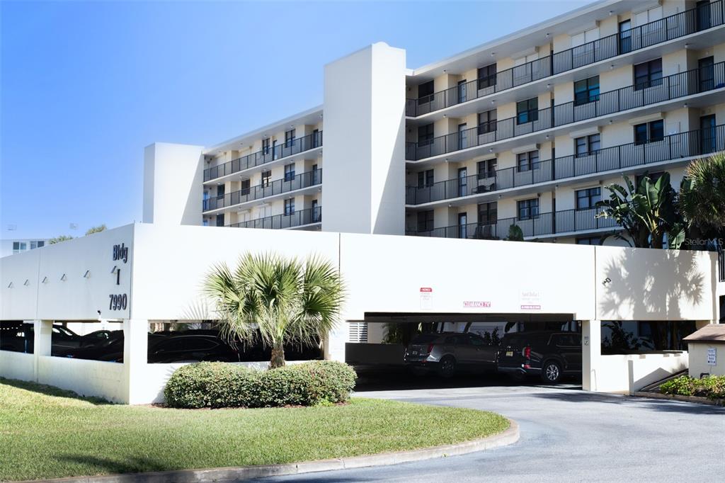 A multi-story apartment building features a covered ground-level parking garage and a palm tree — 7990 A1A S UNIT 404, ST AUGUSTINE, FL