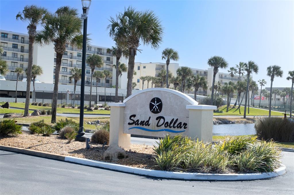 The Sand Dollar sign stands in front of a multi-story building and palm trees — 7990 A1A S UNIT 404, ST AUGUSTINE, FL