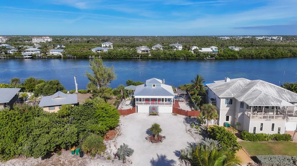 An aerial view shows a waterfront house with a metal roof and a gravel driveway — 440 BOCILLA DRIVE, PLACIDA, FL