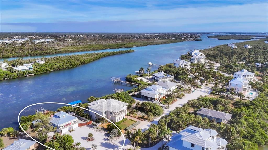 An aerial view shows a coastal property with multiple houses near a waterway — 440 BOCILLA DRIVE, PLACIDA, FL