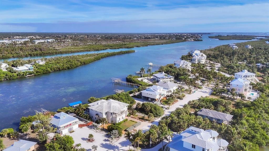 An aerial view shows several waterfront homes surrounded by lush vegetation along a winding waterway — 440 BOCILLA DRIVE, PLACIDA, FL