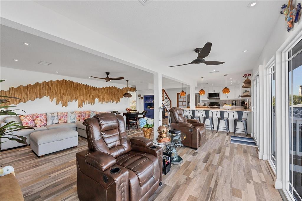 An open-concept living room and kitchen feature wood-look flooring, a textured wall art installation, and recliners — 440 BOCILLA DRIVE, PLACIDA, FL