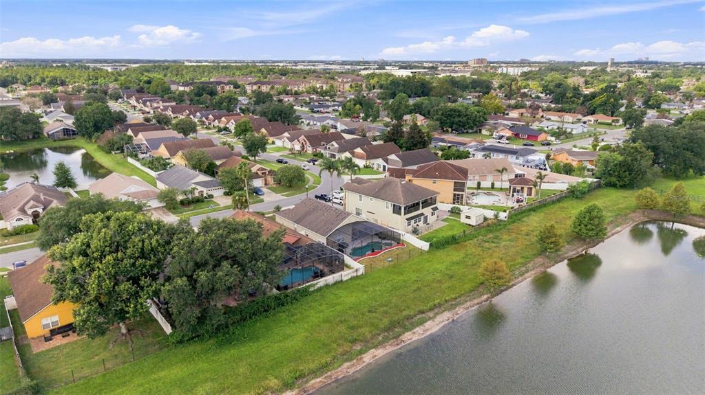 An aerial view shows suburban houses with swimming pools situated along a grassy pond bank — 6539 CHERRY GROVE CIRCLE, ORLANDO, FL