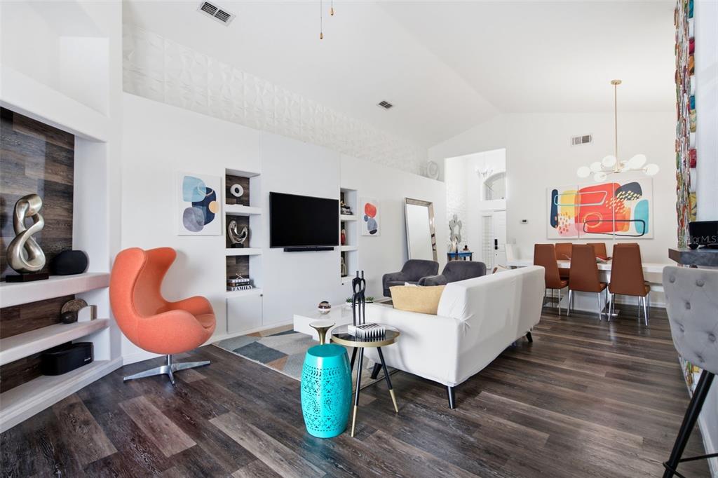 A modern living and dining area with white walls, dark wood floors, and colorful accents — 6539 CHERRY GROVE CIRCLE, ORLANDO, FL