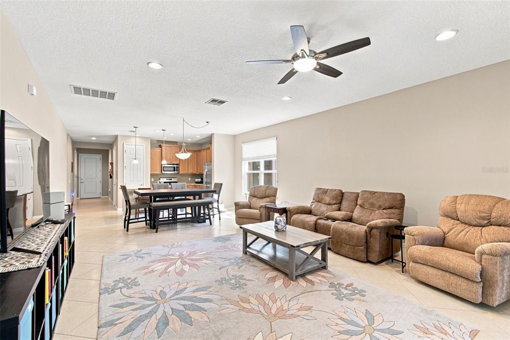 An open-concept living room and dining area with tile floors, neutral walls, and brown furniture — 1055 HARBOR RIDGE DRIVE, KISSIMMEE, FL