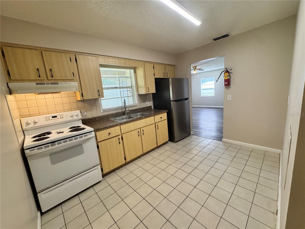 A kitchen with light wood cabinets, white appliances, and tiled flooring — 1001 CRAWFORD STREET Unit 1, LEESBURG, FL