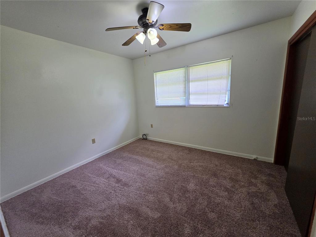 An empty bedroom features white walls, brown carpet, a ceiling fan, and a window with blinds — 1103 N CRYSTAL TERRACE, PLANT CITY, FL