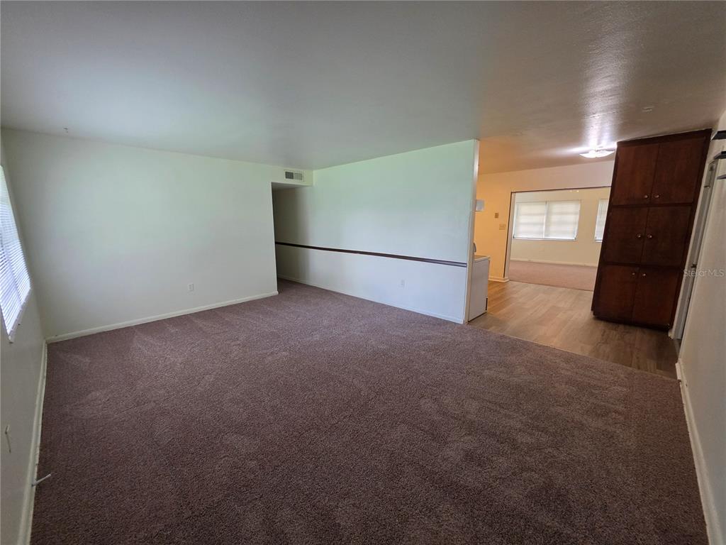 A living room with brown carpet, white walls, and a view into an adjacent room — 1103 N CRYSTAL TERRACE, PLANT CITY, FL