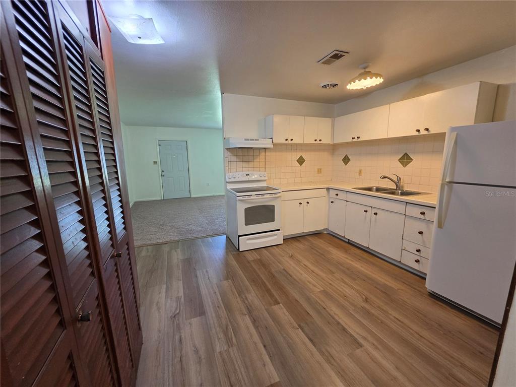 A kitchen with white cabinets, a white stove, a refrigerator, and wood-look flooring — 1103 N CRYSTAL TERRACE, PLANT CITY, FL