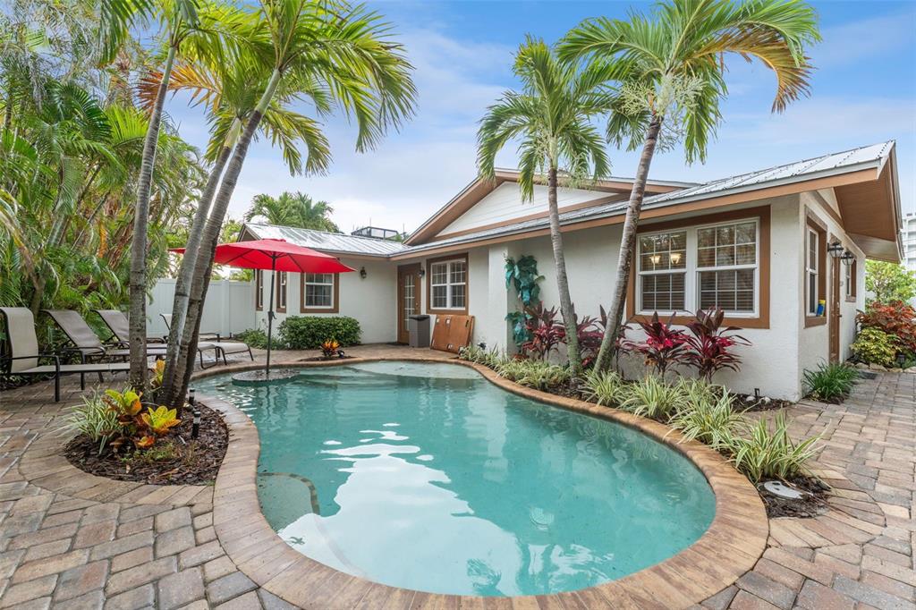 A backyard features a kidney-shaped swimming pool, palm trees, and a patio with lounge chairs — 201 54TH STREET, HOLMES BEACH, FL