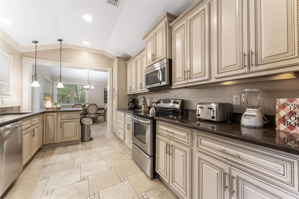 A kitchen with light-colored cabinets, stainless steel appliances, dark countertops, and tiled flooring — 201 54TH STREET, HOLMES BEACH, FL