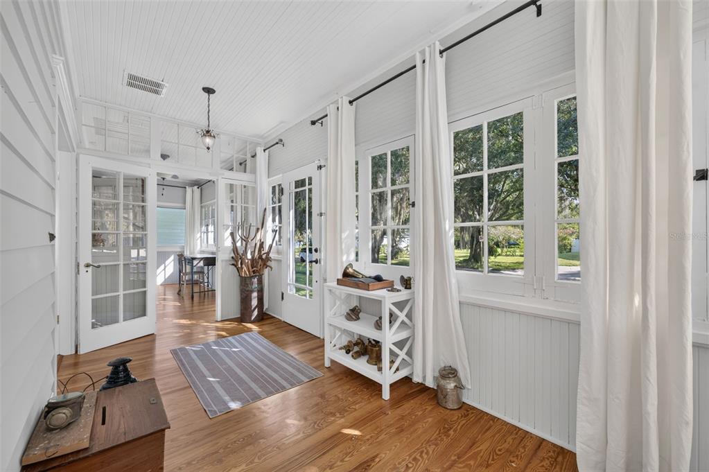 A sunroom with white beadboard walls, wood floors, large windows, and white curtains — 443 BROADVIEW AVENUE, WINTER PARK, FL