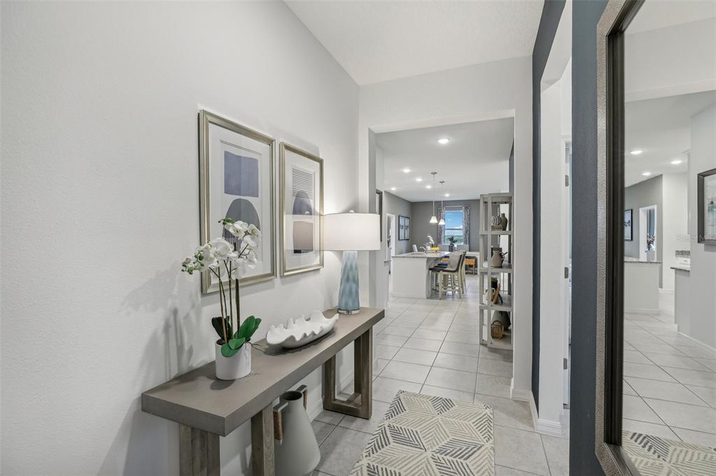 A bright entryway features a console table, wall art, and a view into the kitchen — 5812 CLIFFBOW LOOP, LEESBURG, FL