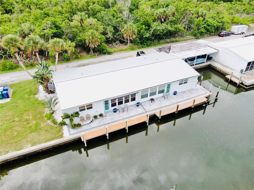 An aerial view shows a white house with a metal roof beside a canal dock — 713 SAINT JUDES DRIVE S UNIT 2, LONGBOAT KEY, FL