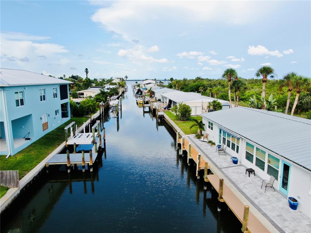 An aerial view of a canal lined with houses, docks, and palm trees under a sky — 713 SAINT JUDES DRIVE S UNIT 2, LONGBOAT KEY, FL