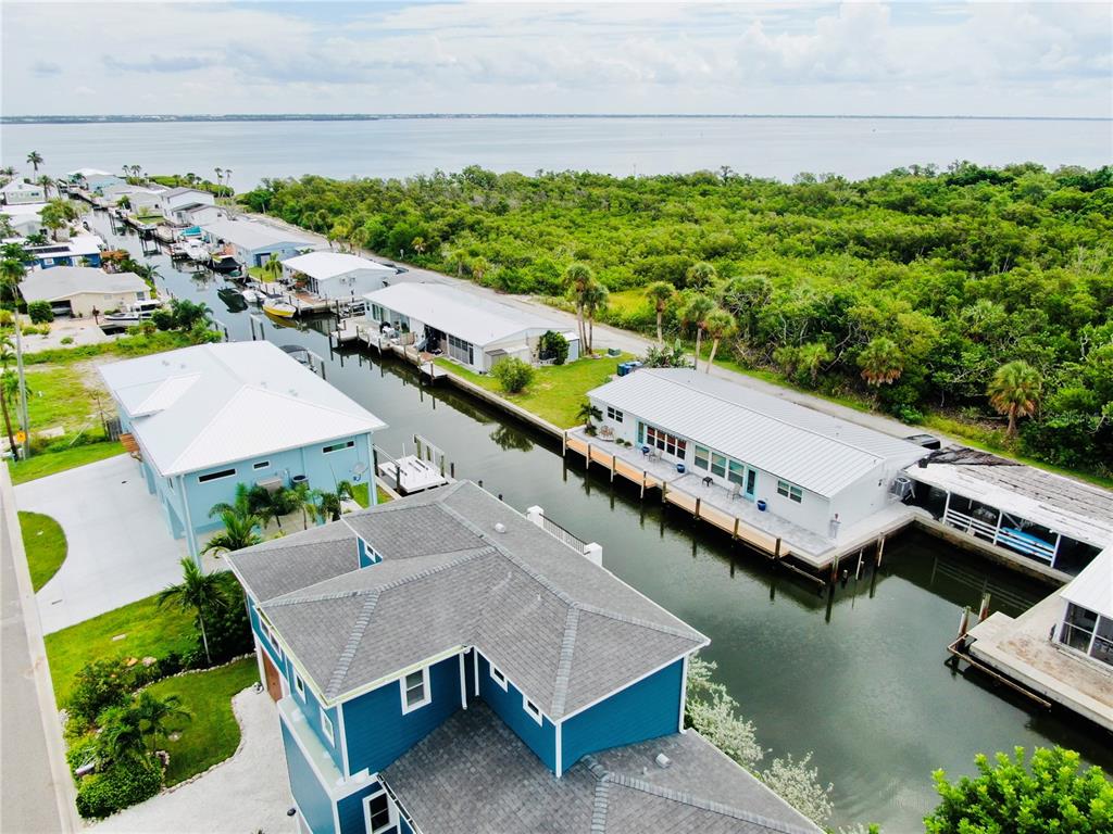 An aerial view shows several waterfront homes along a canal leading to a large bay — 713 SAINT JUDES DRIVE S UNIT 2, LONGBOAT KEY, FL