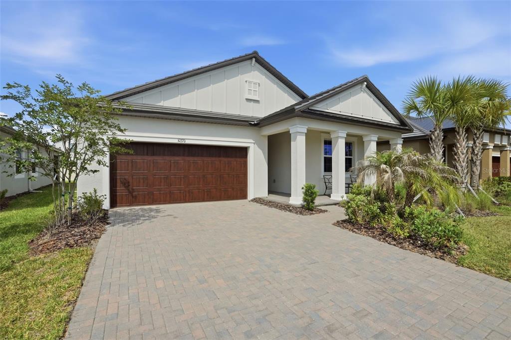 A single-story house with a paved driveway, a two-car garage, and a covered front porch — 10770 TUPPER CAY DRIVE, SAN ANTONIO, FL