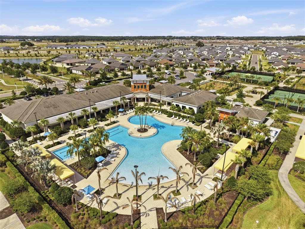 An aerial view of a community clubhouse featuring a large swimming pool and tennis courts — 10770 TUPPER CAY DRIVE, SAN ANTONIO, FL