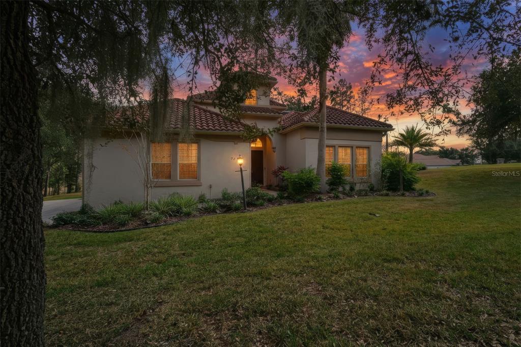 A single-story stucco house with a tile roof sits on a grassy lot at sunset — 2257 N HICKORY GLEN POINT, HERNANDO, FL