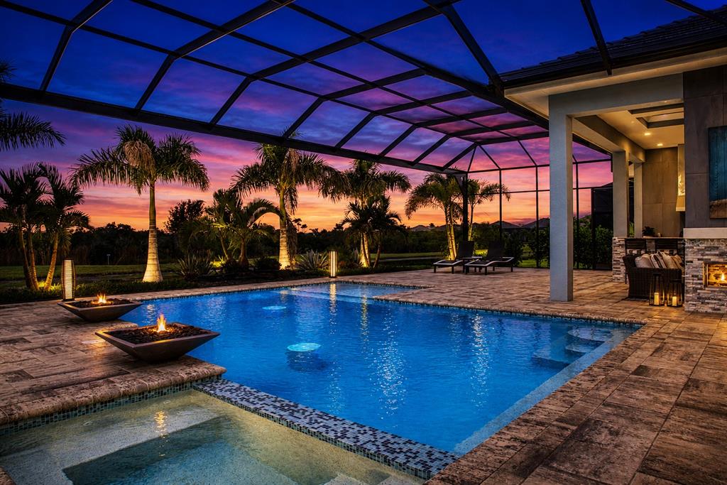 A swimming pool and spa sit under a screened enclosure at sunset with palm trees — 7935 BOWSPIRIT WAY, BRADENTON, FL