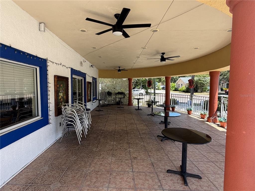 A covered outdoor patio features tiled flooring, multiple round tables, and several ceiling fans — 1501 CLEARWATER LARGO ROAD N, LARGO, FL