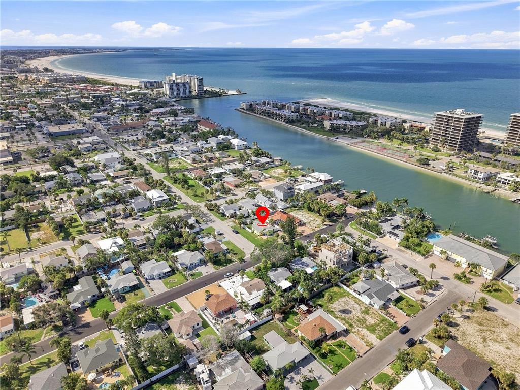 An aerial view shows a residential neighborhood near a coastal waterway and beach — 600 79TH AVENUE, ST PETE BEACH, FL