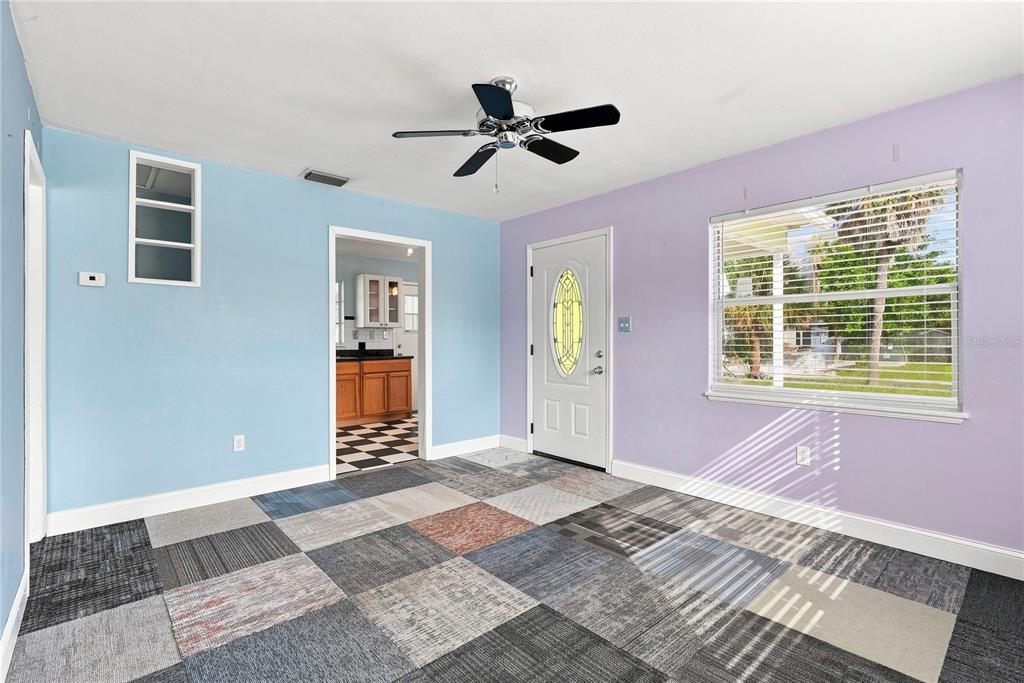A room with blue and purple walls, a ceiling fan, and multi-colored carpet tiles — 600 79TH AVENUE, ST PETE BEACH, FL