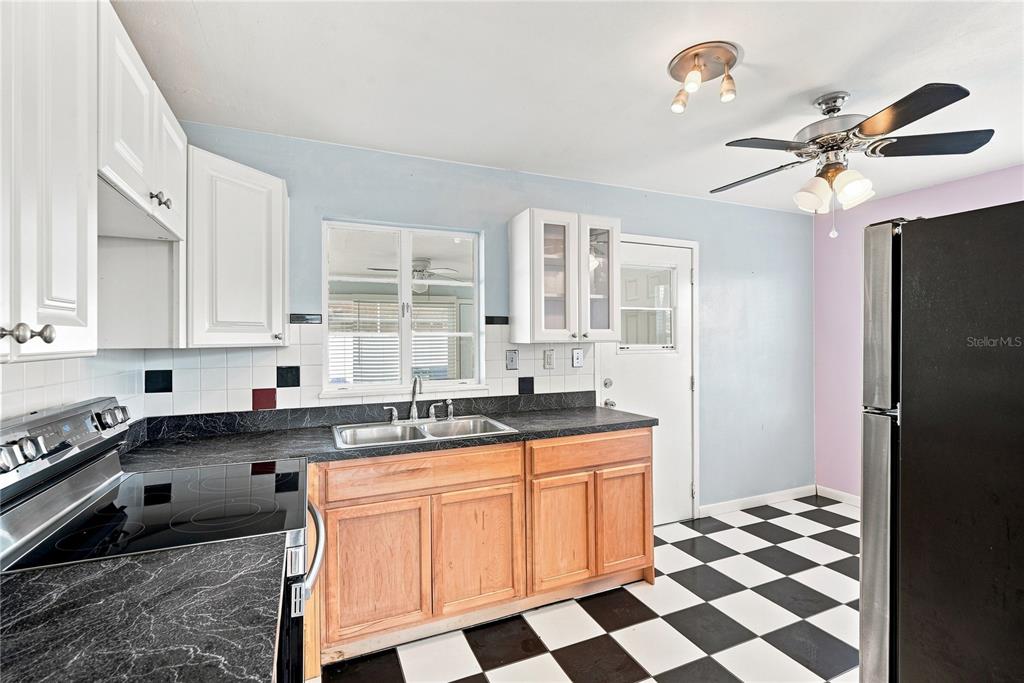 A kitchen features wood cabinets, black countertops, white upper cabinets, and a black-and-white checkered floor — 600 79TH AVENUE, ST PETE BEACH, FL