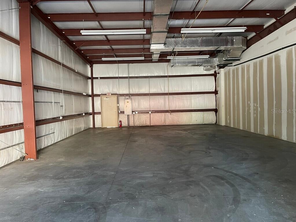 An empty industrial warehouse space features exposed steel beams, concrete floors, and white wall insulation — 2433 S 86TH STREET, TAMPA, FL