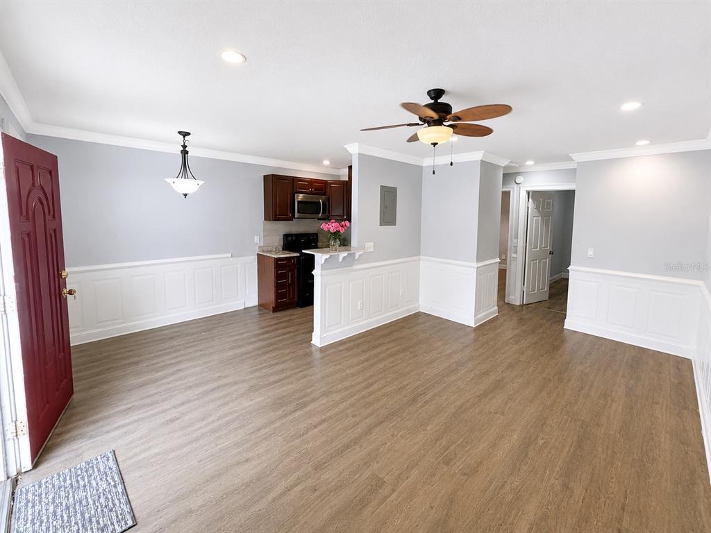 An open-concept living and dining area features wood-look flooring, white wainscoting, and a small kitchen — 4666 KEN KNIGHT DRIVE N, JACKSONVILLE, FL