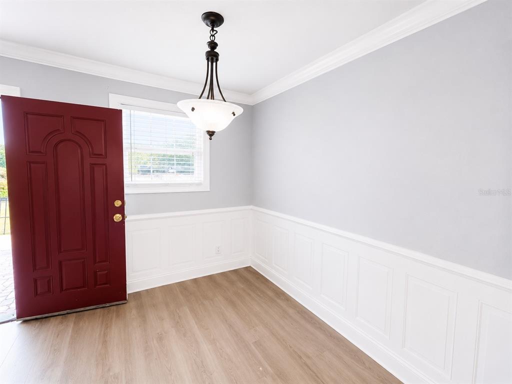 A room with light gray walls, white wainscoting, wood-look flooring, and a red entry door — 4666 KEN KNIGHT DRIVE N, JACKSONVILLE, FL