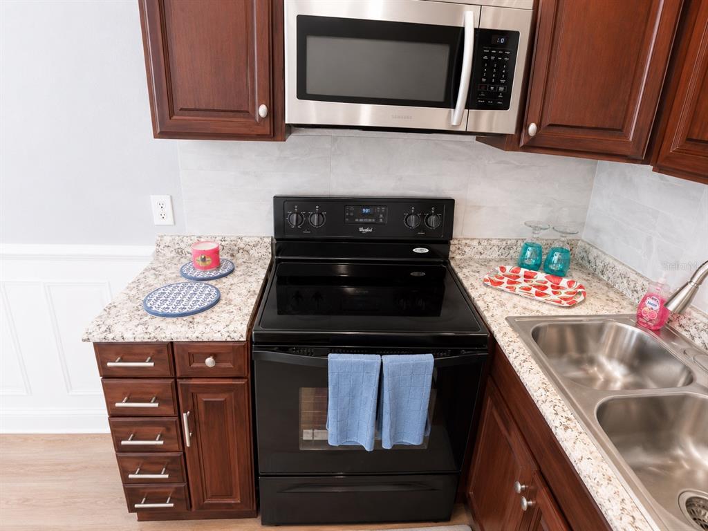 A kitchen features dark wood cabinets, a black stove, a microwave, and granite countertops — 4666 KEN KNIGHT DRIVE N, JACKSONVILLE, FL