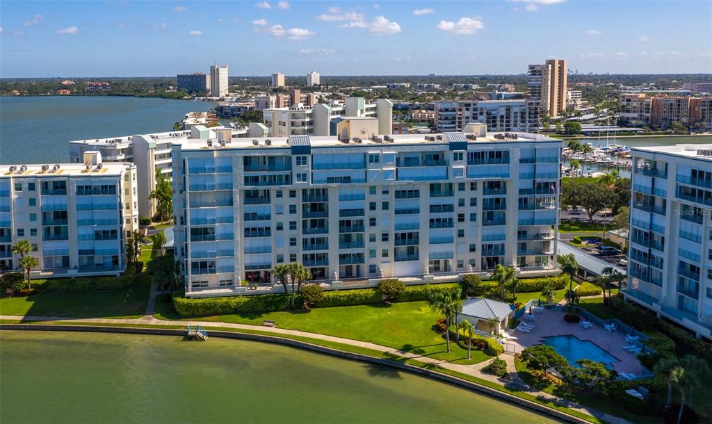An aerial view shows a multi-story apartment complex with a pool and waterfront access — 7974 SAILBOAT KEY BOULEVARD S UNIT 408, SOUTH PASADENA, FL