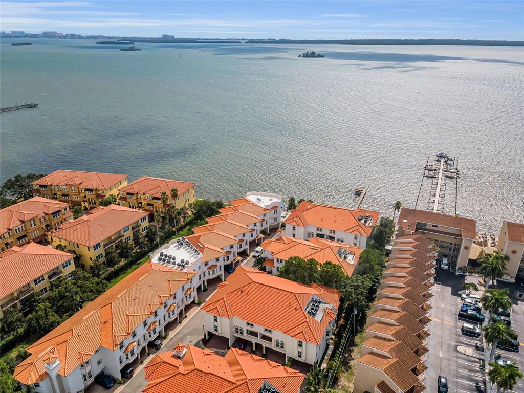 An aerial view shows a waterfront residential complex with orange-tiled roofs and a private pier — 1340 BAYSHORE BOULEVARD UNIT 304, DUNEDIN, FL