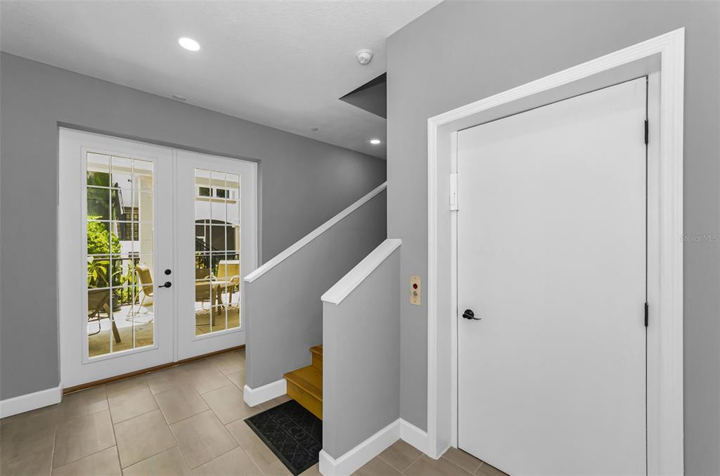 An entryway features gray walls, tile flooring, a white door, and stairs leading upward — 1340 BAYSHORE BOULEVARD UNIT 304, DUNEDIN, FL