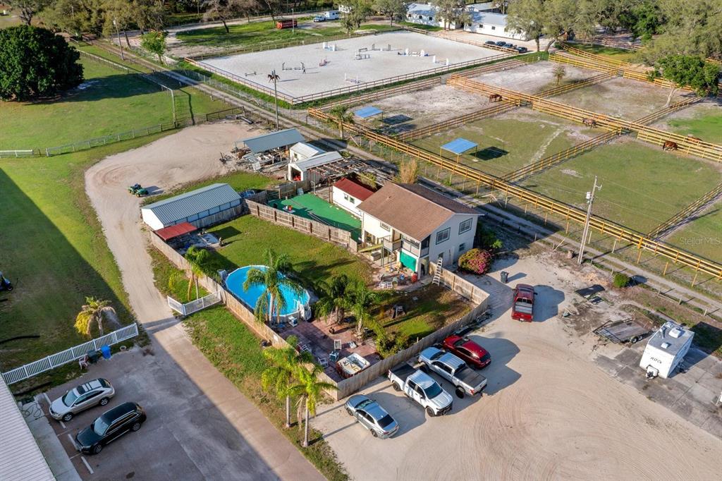 An aerial view shows a house with a pool, fenced paddocks, and a riding arena — 7705 GARDNER ROAD, TAMPA, FL