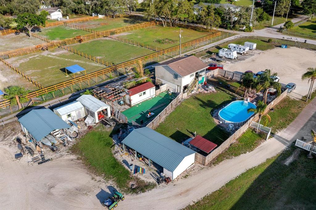 An aerial view of a property featuring a house, pool, outbuildings, and fenced pastures — 7705 GARDNER ROAD, TAMPA, FL