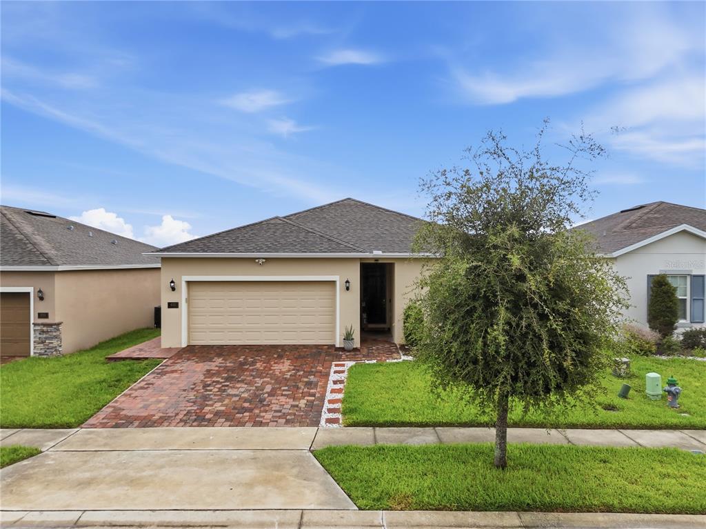A single-story suburban house with a brick driveway, two-car garage, and a front lawn — 490 DISA DRIVE, DAVENPORT, FL