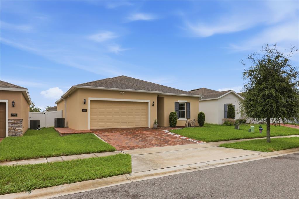 A single-story tan house with a two-car garage and a brick paver driveway — 490 DISA DRIVE, DAVENPORT, FL