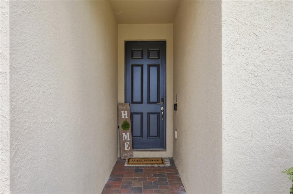 A dark blue front door is set within a recessed entryway with brick flooring — 490 DISA DRIVE, DAVENPORT, FL
