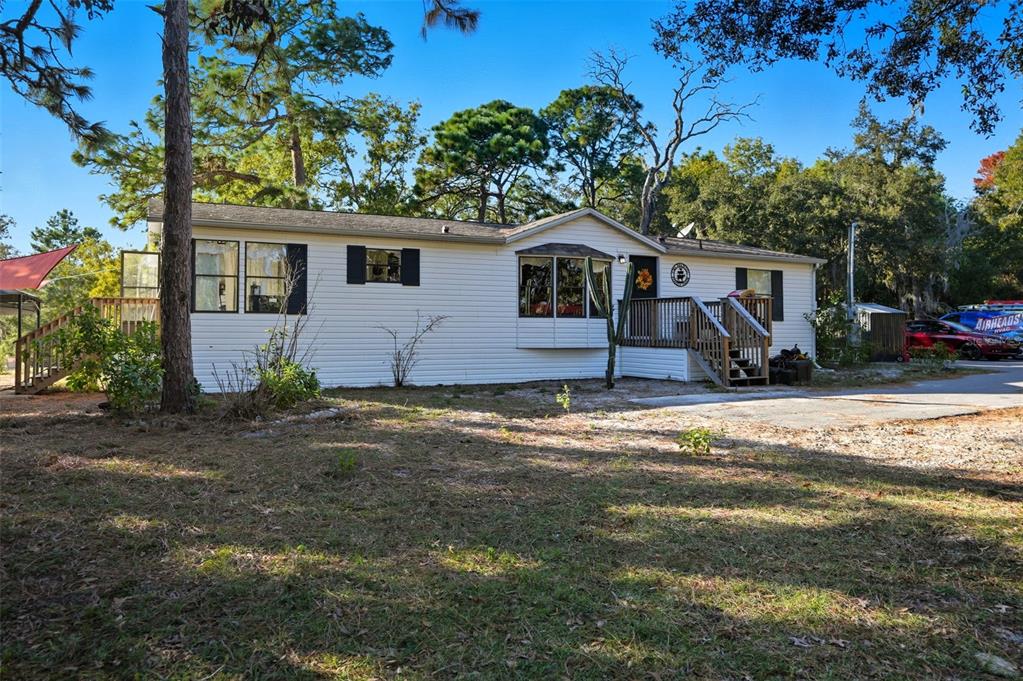 A single-story manufactured home with white siding, a bay window, and a wooden front deck — 17539 EDWIN TERRACE, HUDSON, FL