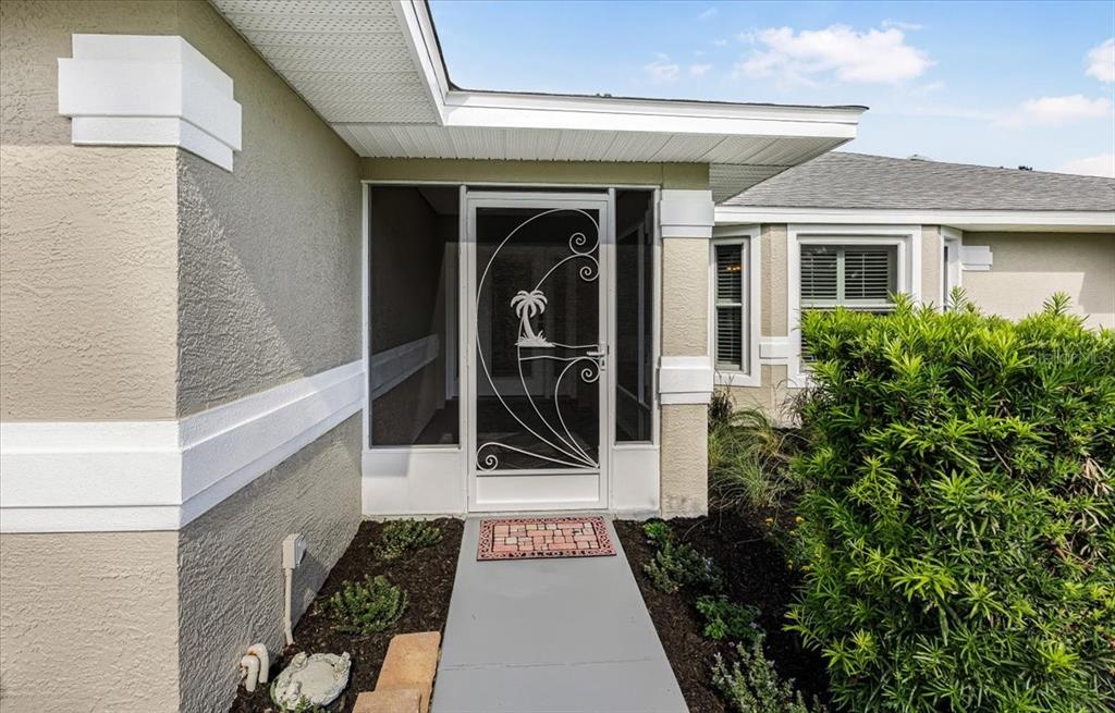 A front entryway features a white screen door with a palm tree design and a walkway — 6501 BORG STREET, LEESBURG, FL