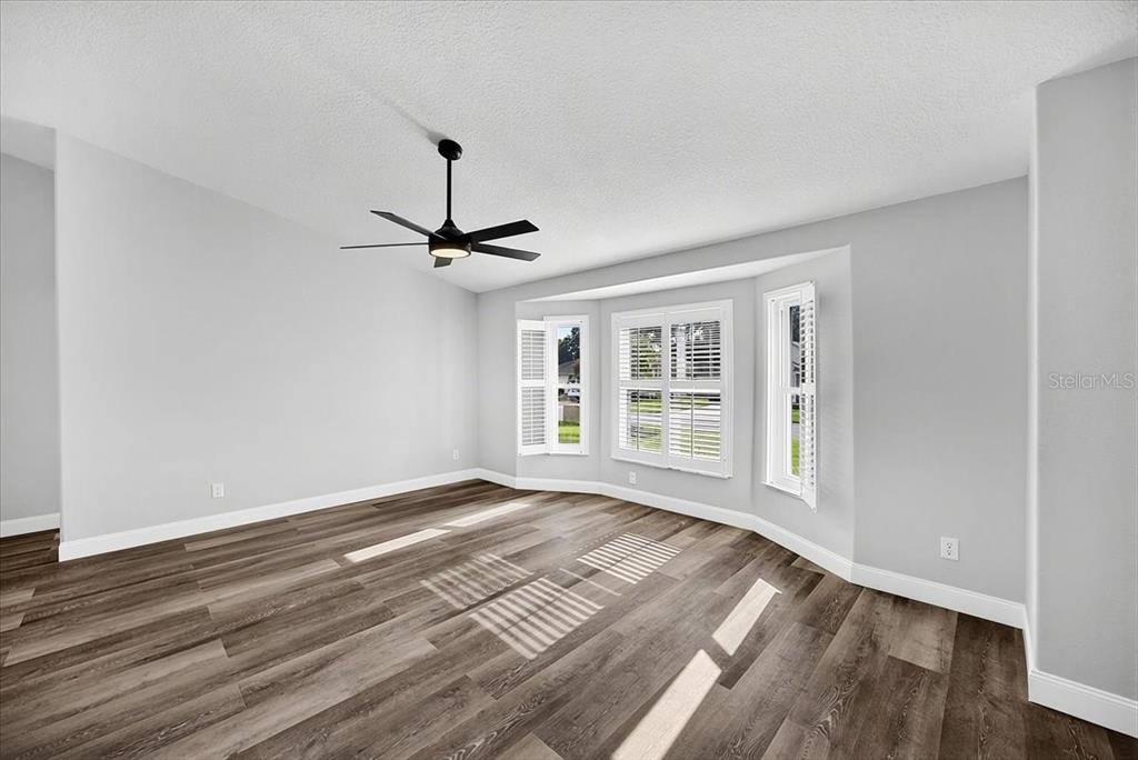 An empty room with gray walls, wood-look flooring, a ceiling fan, and a bay window — 6501 BORG STREET, LEESBURG, FL