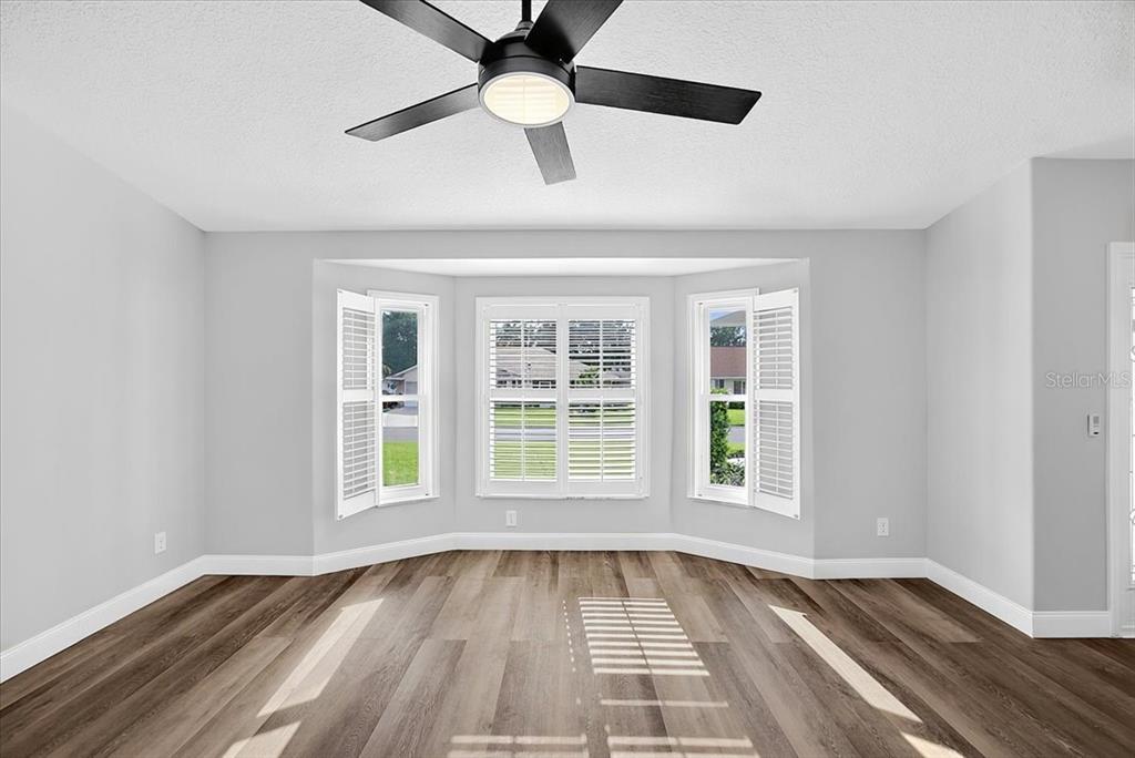 A room with light gray walls, wood-look flooring, a ceiling fan, and a bay window — 6501 BORG STREET, LEESBURG, FL