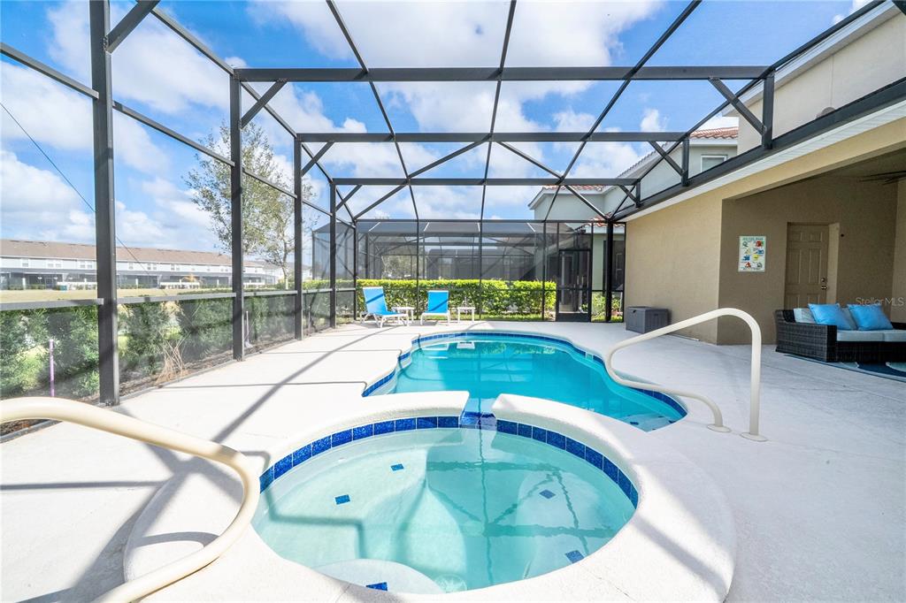A screened-in patio features a swimming pool, a circular hot tub, and outdoor seating — 7560 OAKMOSS LOOP, DAVENPORT, FL
