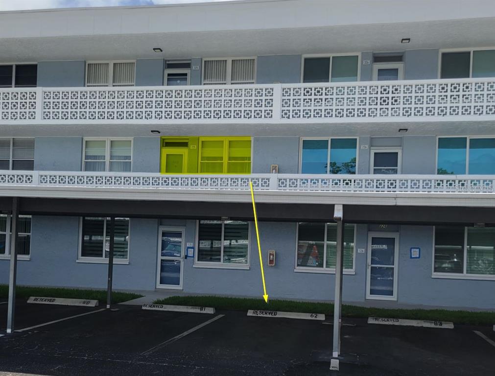An exterior view of a multi-story apartment building with a reserved parking space below — 4715 BAY STREET NE UNIT 225, ST PETERSBURG, FL