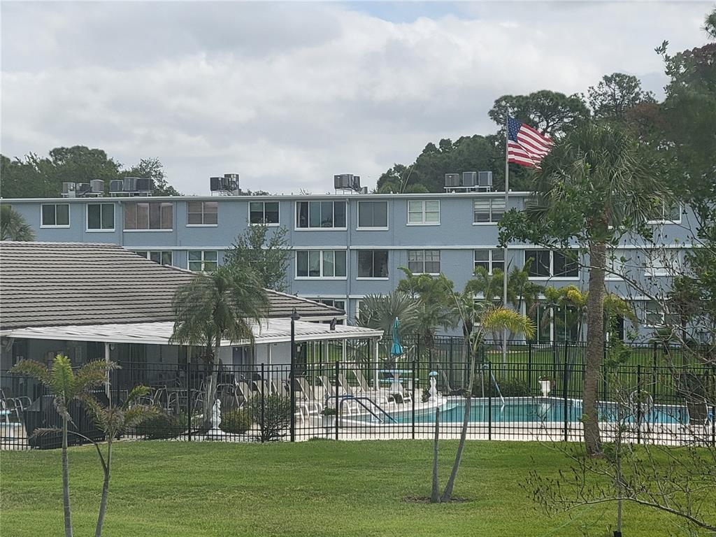 A multi-story blue apartment building stands behind a swimming pool and a grassy lawn — 4715 BAY STREET NE UNIT 225, ST PETERSBURG, FL