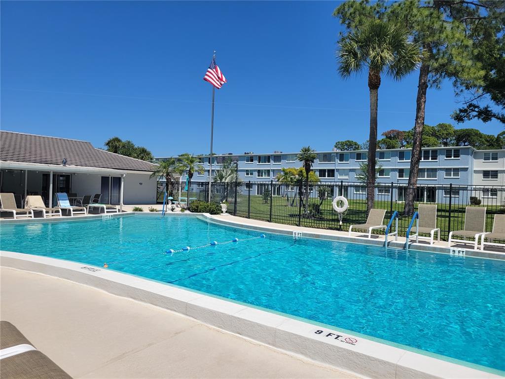 A swimming pool with lounge chairs sits in front of a multi-story apartment building — 4715 BAY STREET NE UNIT 225, ST PETERSBURG, FL